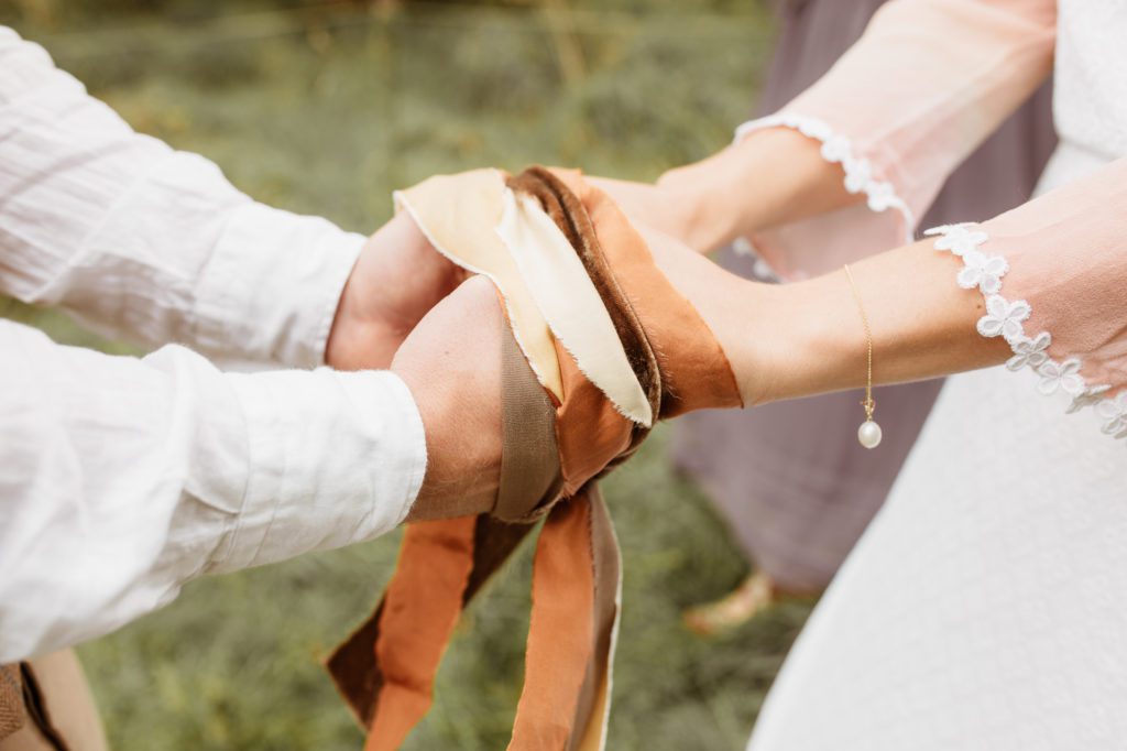 handfasting ceremony, close up on ribbons tying hands.