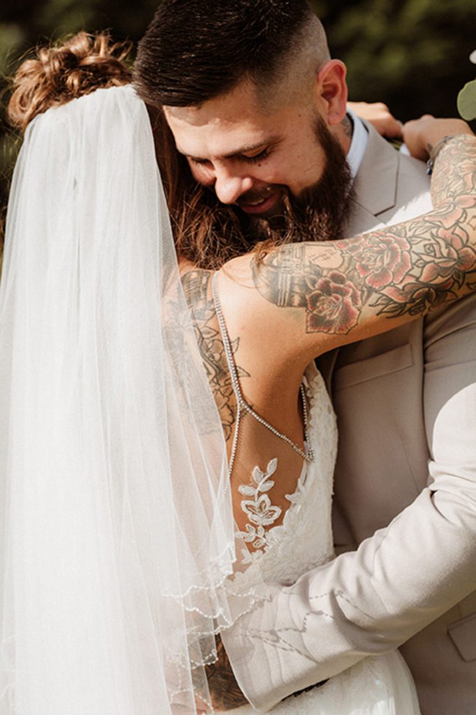 bride and groom embracing. Bride has tattoos.