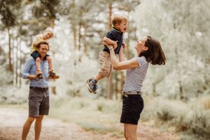 mum throwing little boy in air, outside on woods at Summer