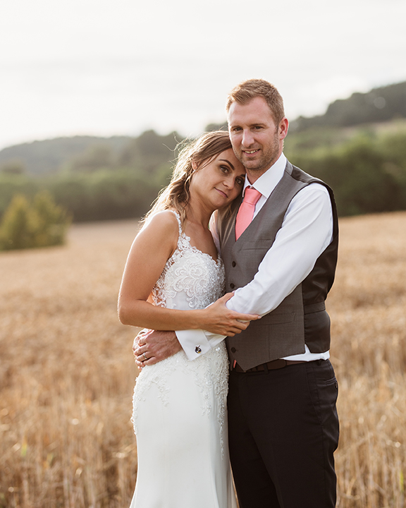 bride and groom having a cuddle outside with fields in background