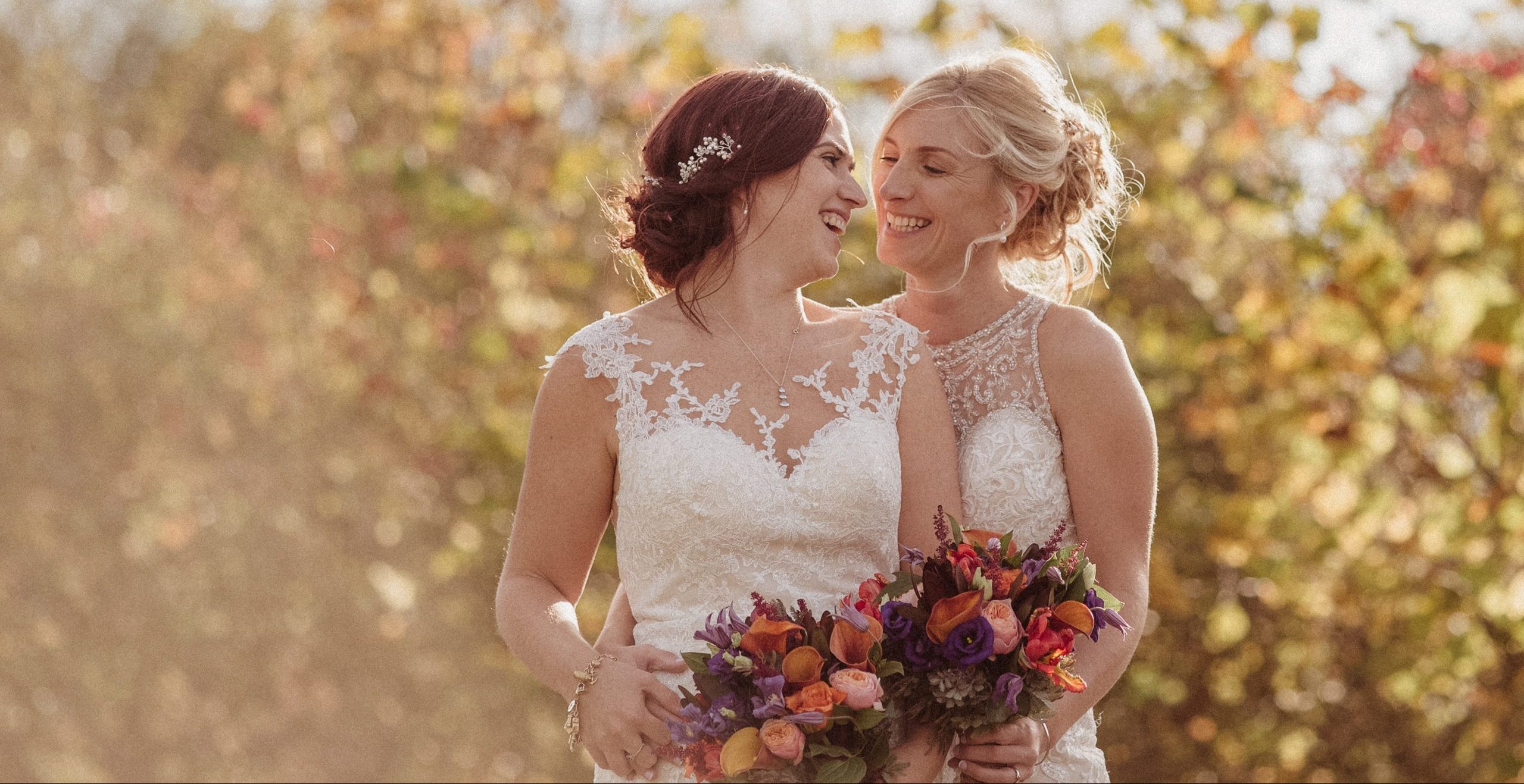 two brides laughing together at their wedding at clock barn