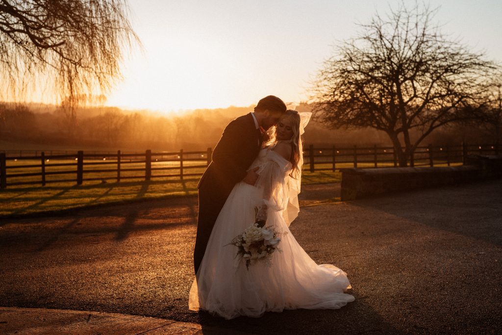 boho bride and groom embracing at sunset, soft golden hour light.