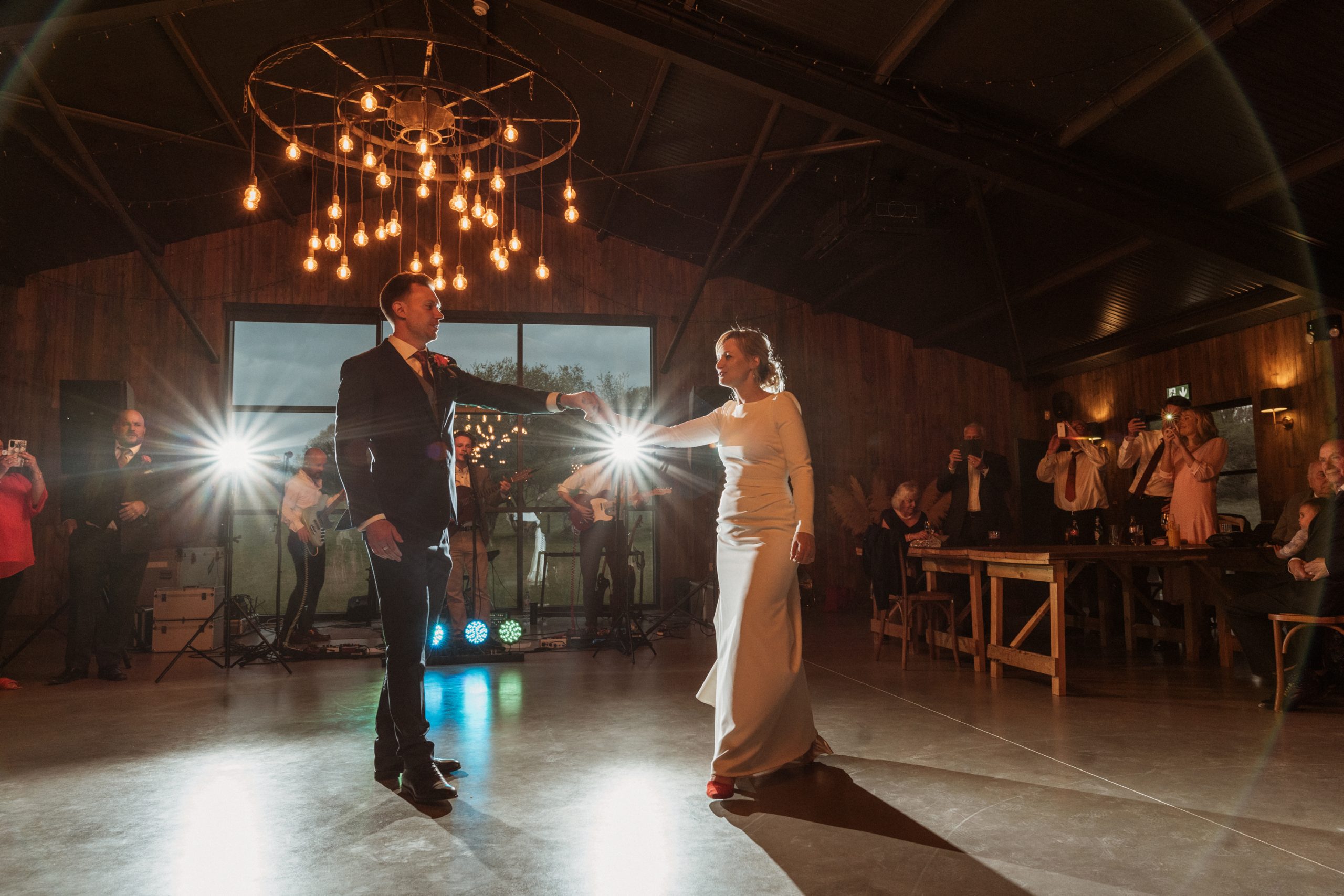 Bride and groom dancing their first dance. Back lit with flash guns in barn at Silchester Farm